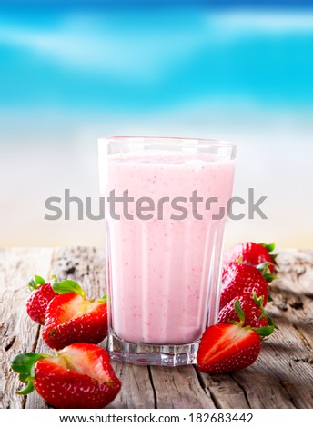 Fresh milk, strawberry drink on wodeen table, assorted protein cocktail with fresh fruits. Summer drink on the beach and blue sky.