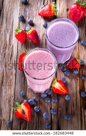 Fresh milk, strawberry and blueberry drinks on wodeen table, assorted protein cocktails with fresh fruits.