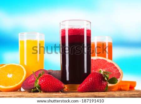 Fresh three juice, orange, strawberry and carrot drink on wooden background with blue sky. Summer concept.