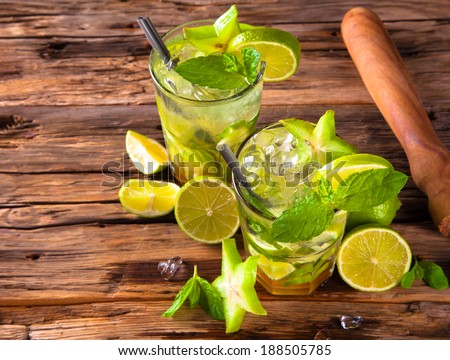 Summer lime cocktail , drink with fresh fruits on wooden table and tropical beach. Blue sky, sea