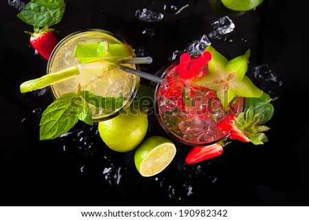 Summer strawberry and lime drinks with fresh fruits on black stone, table.