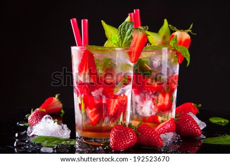 Summer strawberry drinks on black stone, table.
