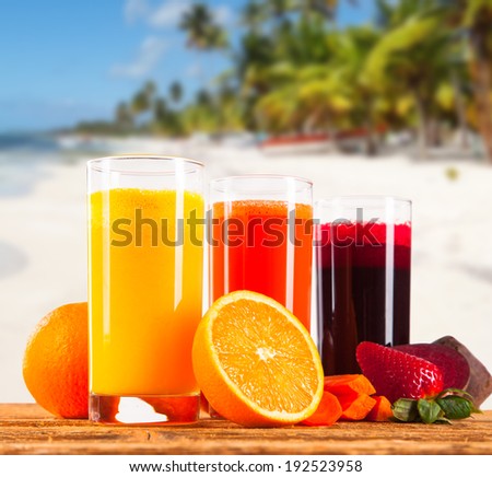 Summer drinks, juice on wooden table. Cocktails with blue sky, tropical beach and fresh fruits.