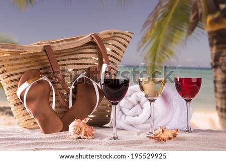 Summer concept, white nad red wine on tropical beach. straw hat, candle Blue sky, sea