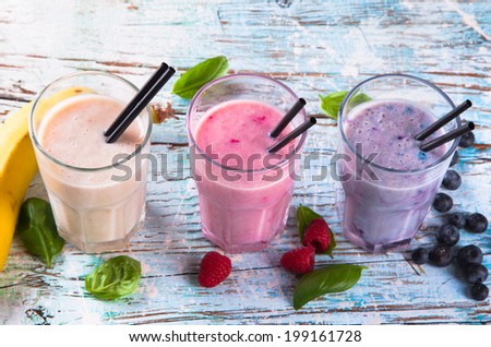 Fresh milk, raspberry and blueberry drinks on wooden table, assorted protein cocktails with fresh fruits. Natural background.