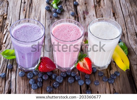 Fresh milk, strawberry, blueberry and banana on wooden table, assorted protein cocktails with fresh fruits. Natural background.