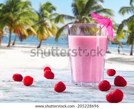 Fresh milk, raspberry, on wooden table, assorted protein cocktails with fresh fruits. Tropical beach background.
