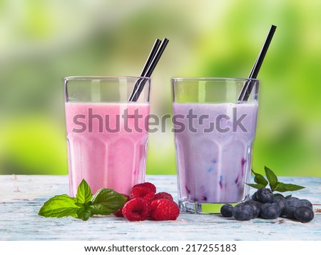 Fresh milk, raspberry, blueberry drinks on wooden table, assorted protein cocktails with fresh fruits.