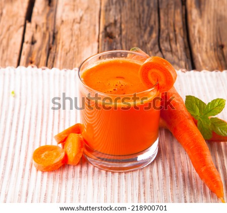 carrot juice and carrot segments on a wooden background