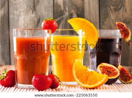 Fresh juice, mix fruits orange, strawberry, lime, and ficus drinks on wood plants background.