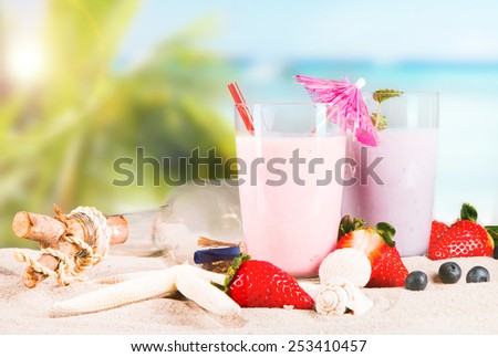 Fresh milk, strawberry, blueberry drinks on wooden table, assorted protein cocktails with fresh fruits and tropical beach background.
