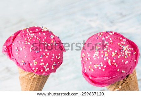 Fruit ice-cream in ice-cream cones on wooden table