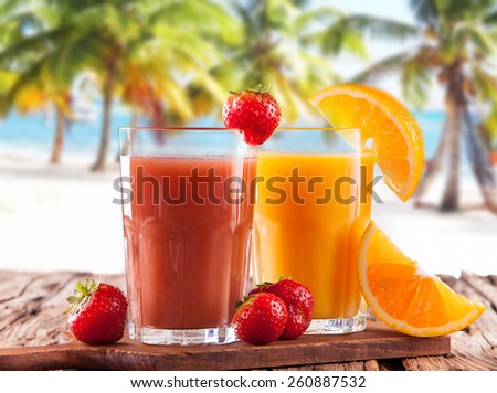 Fresh juice, mix fruits, strawberry and orange drinks on wood plants with tropical beach background
