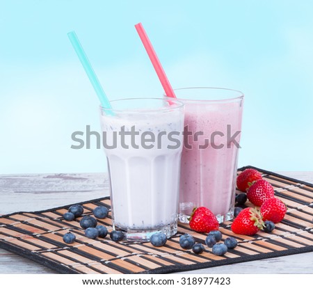 Fresh milk, blueberry and strawberry drinks on wooden table, assorted protein cocktails with fresh fruits.