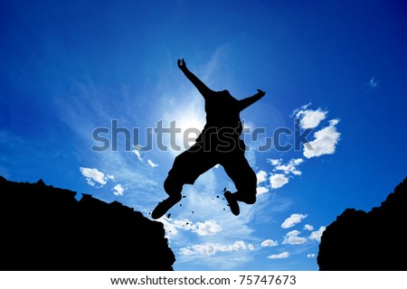 man jumping from a cliff over vivid blue sky