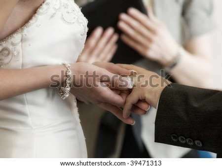 A bride placing a ring on her groom\'s hand as they get married