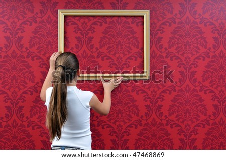 girl is hanging up a picture frame