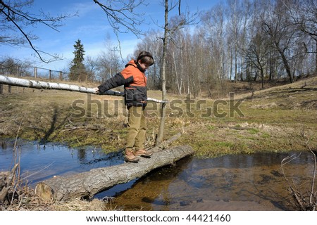 The beginning of spring, boy on the old bridge over water