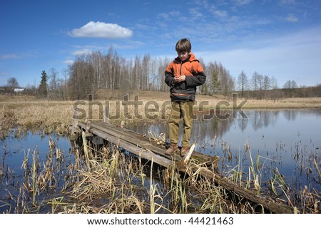 The beginning of spring, boy on the old bridge over water