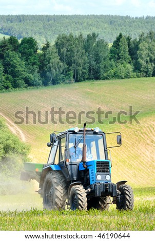 Country road and a tractor in the field on a summer day