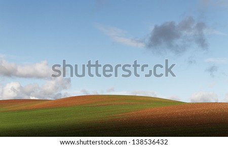 Hill farmland with light-weight clouds.