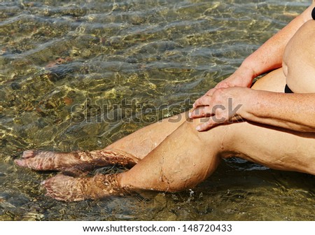 Grandmother is healing ill legs in the salt water of Moinaki salt lake.