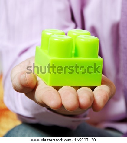 Young man is playing with multicolored toy blocks.