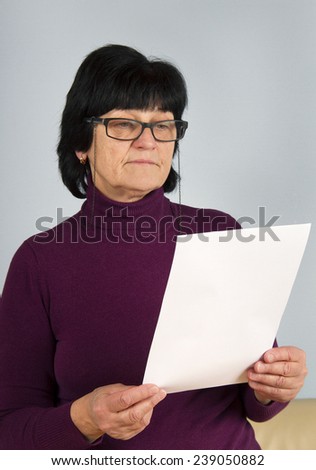 Adult woman with glasses watching to the sheet of paper.