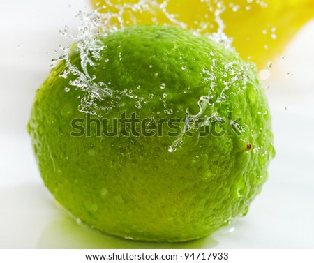 Fruits washing, water splash above ripe lemon and lime.