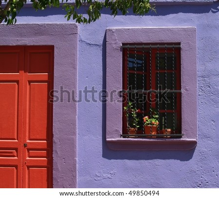 Mediterranean house facade with red door and window