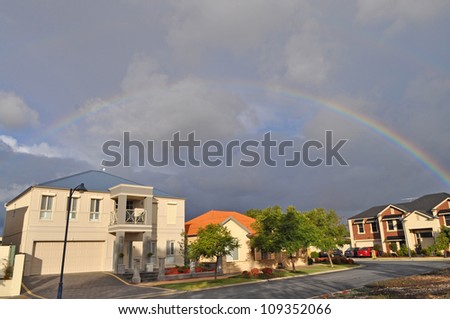 Rainbow on dark sky. Modern Australian house