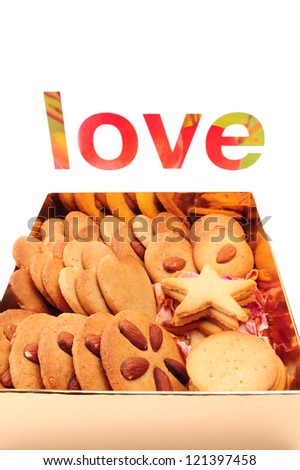 Assorted biscuits in a gold box with the word LOVE, isolated on white background. Gift packaging. Valentine gift