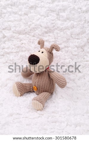 Beige crocheted bear sitting on the white cloth