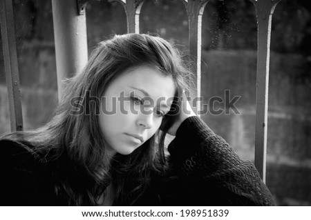 Outdoor portrait of a sad young woman looking thoughtful about troubles, monochrome