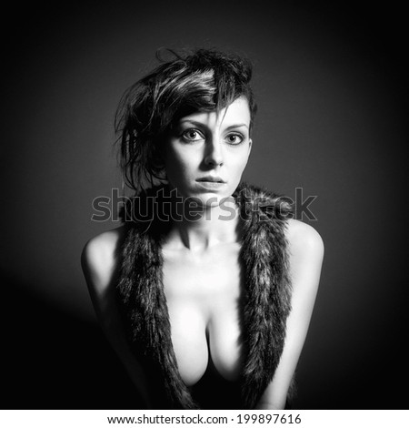 Closeup monochrome fashion portrait of an attractive young woman in front of dark studio background