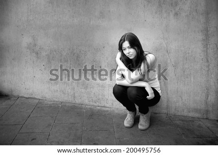 Outdoor portrait of a sad teenage girl looking thoughtful about troubles, monochrome photo