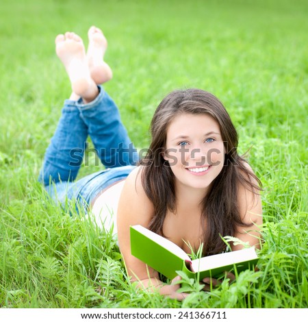 Portrait of a beautiful young woman reading a book, outdoor photo taken in summer