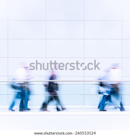 Unrecognizable business people in a fair hall, intentional motion blur, blue tinted photo