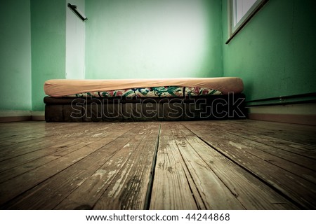 Mattress in green painted room with floor from wooden planking