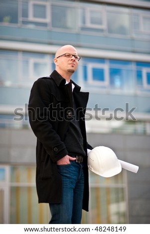 Architect with helmet and plan in front of a modern facade