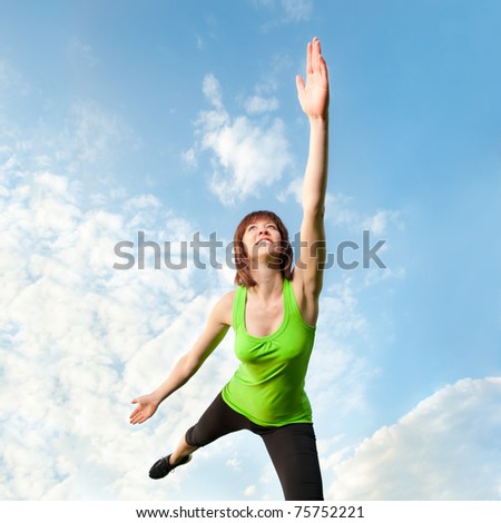 Beautiful athletic woman balancing in front of blue sky
