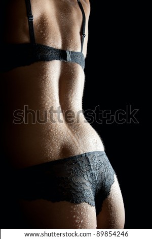 Beautiful back of a  woman wearing undies and bra in front of black background