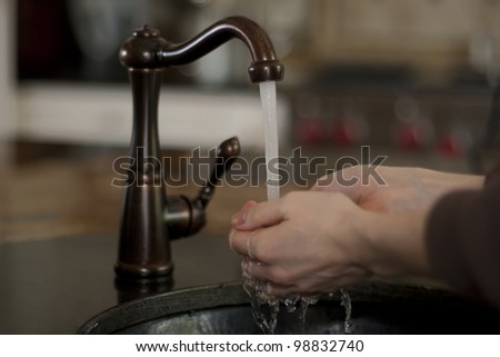 Close-up of human hands being washed under stream of pure water from tap