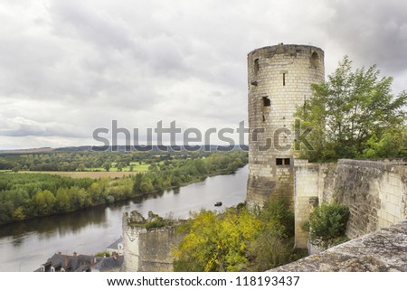 Old ruined public domain castle tower and brick yellow  wall in the background of the autumn sky landscape with river. Cloudy autumn day. Soft art focus