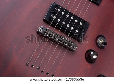 Red retro vintage wooden solid body electric mass production guitar with  strings and pickups background. Selective art focus