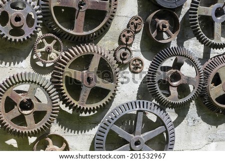 Time machine concept. Cogwheels and gears hang on a wall. Iron wheels are covered with a rust, a dust and a web