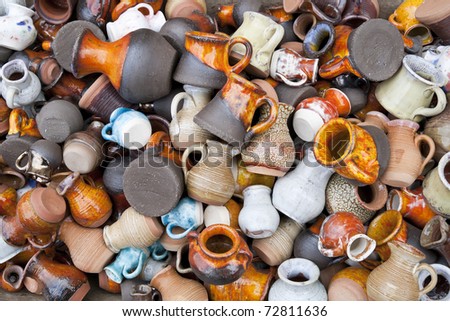 Background from small ceramic multicolored jugs and cups. Mass production, selective focus