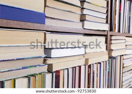 Old books on a shelf perspective background. Strong selective focus. Mass production