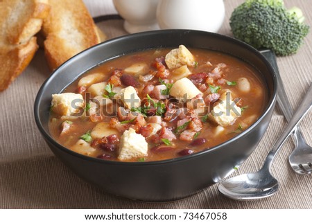 Delicious soup with chunks of meat, beans and croutons in a bowl