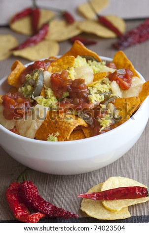 A bowl of vegetarian nachos with cheese, salsa sauce and jalapenos